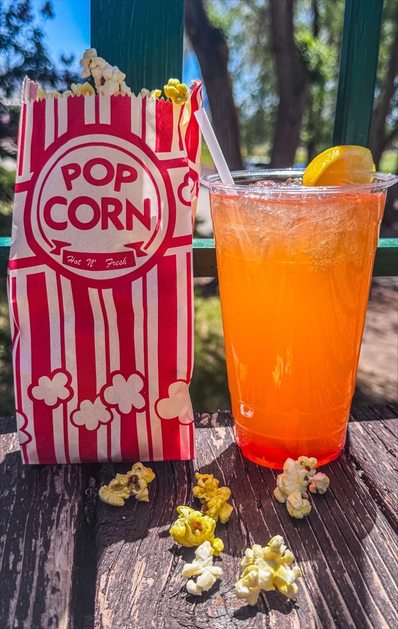 A bag of popcorn next to a fruity dirty soda on the patio rail
